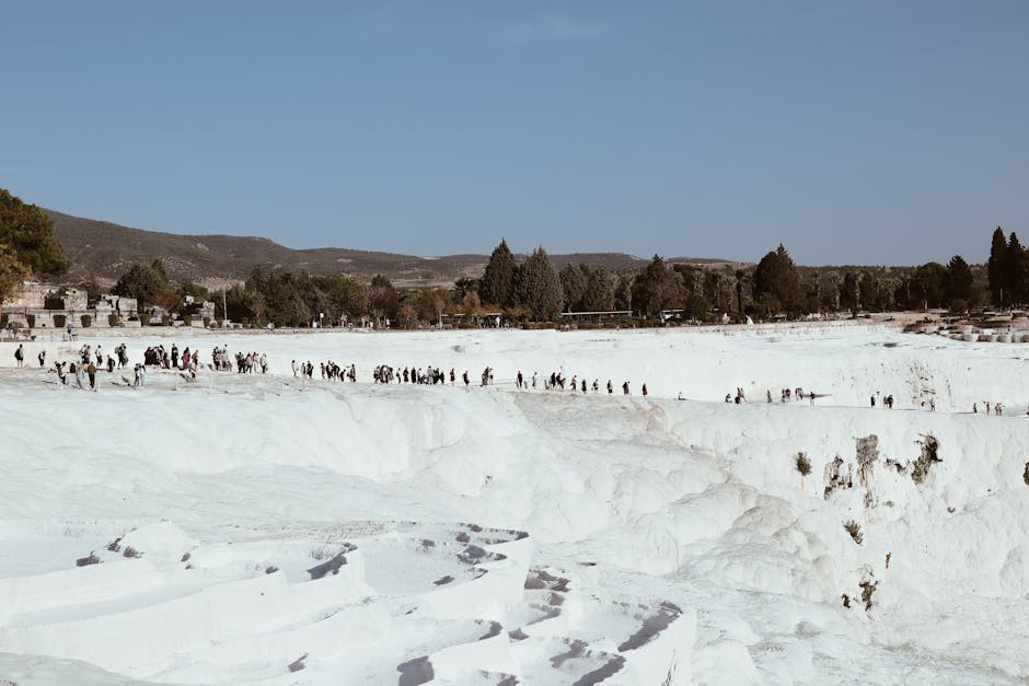 Visitors walking on the unique white travertine terraces of Pamukkale, Denizli, Türkiye.