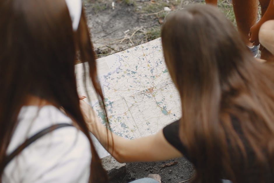 Two women study a map outdoors, planning their hiking route.
