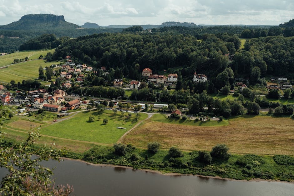 Stunning aerial view of a serene valley town surrounded by lush forests and a winding river.