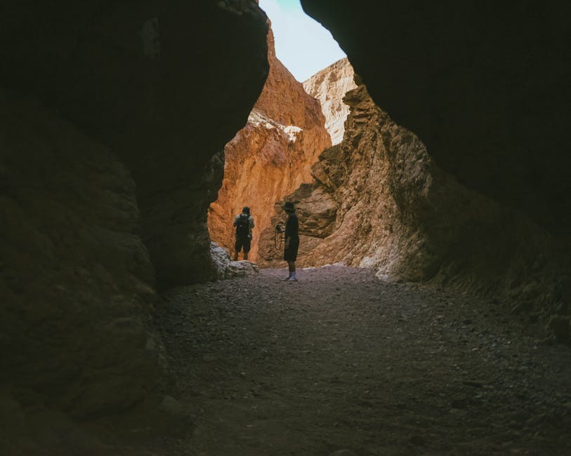 Two hikers venture through a rocky canyon illuminated by natural light, capturing the essence of exploration.
