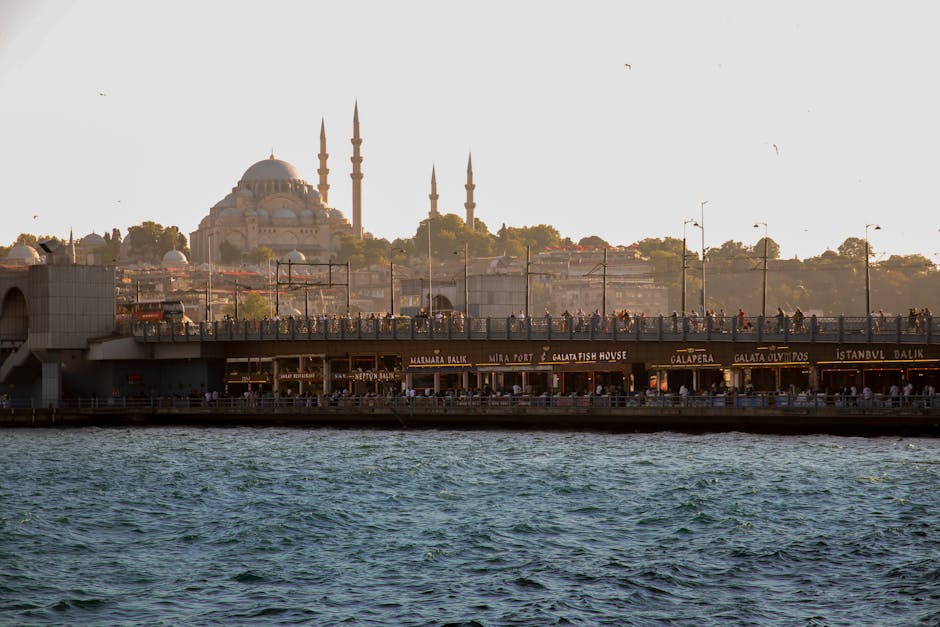 View of Galata Bridge and Süleymaniye Mosque silhouetted at sunset in Istanbul.