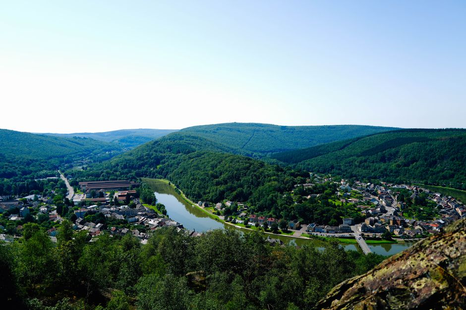A panoramic view of a charming village nestled in a lush green valley by a river.