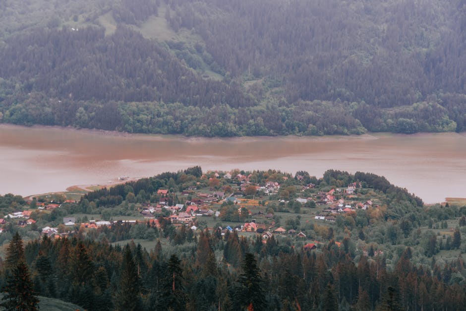 A picturesque aerial view of a village surrounded by lush hills and a winding river.
