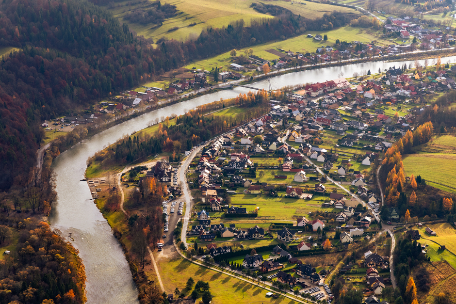 A scenic aerial image highlighting a tranquil riverside village amidst vibrant fall colors.