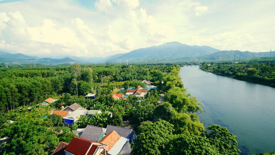 Aerial view of a tranquil river valley surrounded by lush greenery and scattered houses.